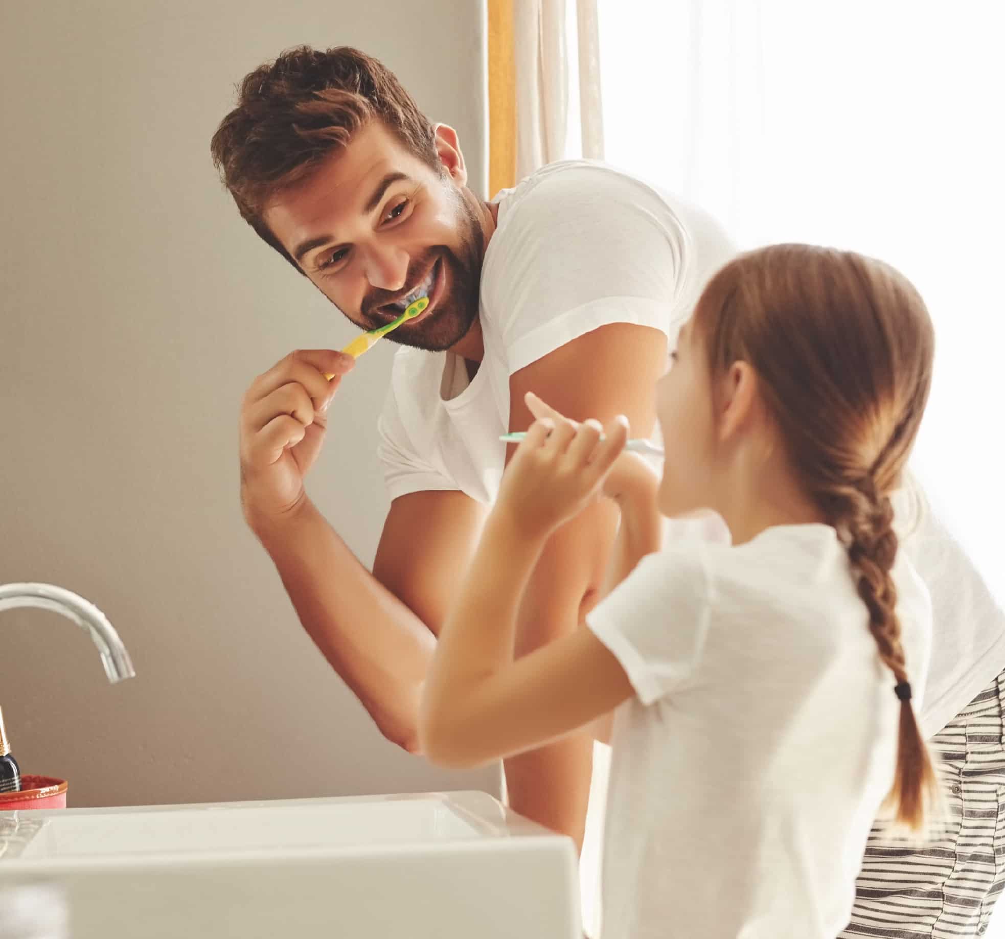 Father and daughter brushing their teeth
